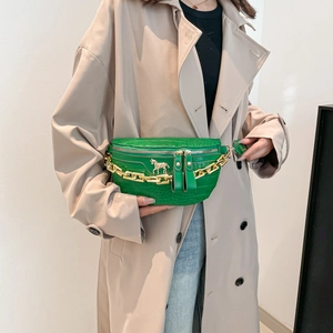 Sac poitrine vert effet croco avec chaîne dorée porté sur un mannequin en trench-coat