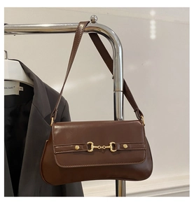 Detail of dark brown leather baguette bag featuring a vintage golden horsebit buckle