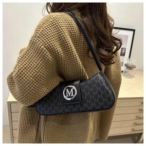 Gros plan détaillé d'un sac baguette noir avec motif M en relief et boucle en métal argenté