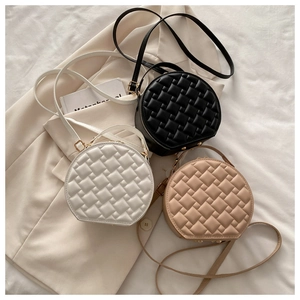 Detailed view of round woven crossbody bags in black, white, and beige with gold hardware