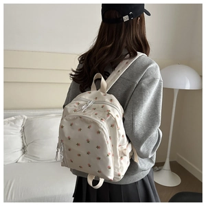Detail view of cream canvas backpack with pink floral print worn in a cozy home setting
