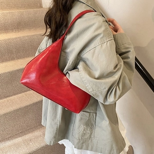 Minimalist red leather hobo underarm bag with silver hardware on model shoulder