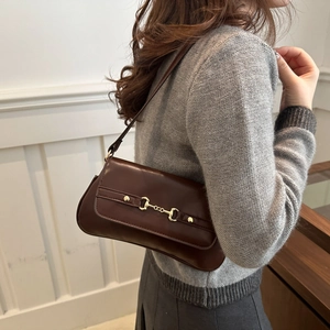 Brown leather baguette bag with horsebit gold buckle accessory worn as underarm shoulder bag