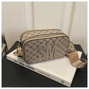 Détail d'un sac bandoulière carré avec monogramme marron et large bandoulière en tissu