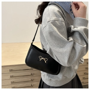 Detailed view of black crescent underarm bag with gold bow clasp and smooth leather texture