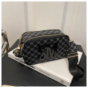 Détail du sac caméra en toile monogramme avec lettres 3D et fermoirs métalliques dorés