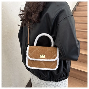 Detail of brown suede crossbody bag with white shearling trim and gold twist lock