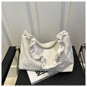 Sac nuage plissé français à motif marbré posé sur un livre et chaise en cuir