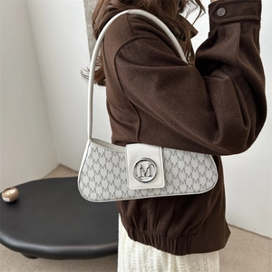 Sac baguette blanc avec imprimé M gris et boucle argentée sur un manteau en laine marron
