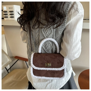 Detail of vintage brown suede crossbody bag with white plush trim and diamond stitching