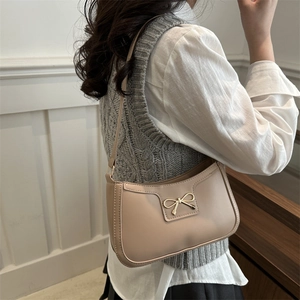 French style beige crescent underarm bag with a golden bow buckle shown on a model