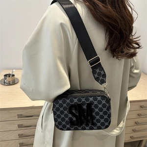 Petit sac carré noir avec monogramme, logo SM et bandoulière en nylon large