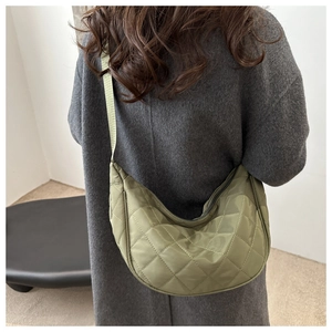 Sac croissant en nylon matelassé vert olive porté en bandoulière sur un manteau noir
