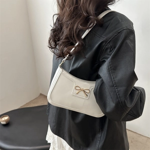 White crescent underarm bag with gold bow detail and minimalist French chic style