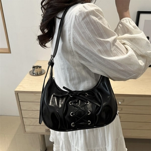 Black half-moon shoulder bag with ribbon lace-up detail and glossy finish shown on model