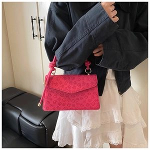 Detail of rose red square handbag with clover embossed texture and knot strap