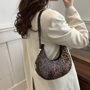 Fashionable leopard print crescent hobo bag with silver hardware on a model's shoulder