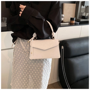 Detail of white handbag featuring embossed floral texture and elegant tassel accent