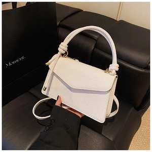 Detail of white leather crossbody bag with embossed clover patterns and gold hardware