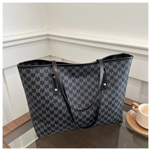 Gros plan sur le motif monogramme et les anses en cuir du grand sac fourre-tout