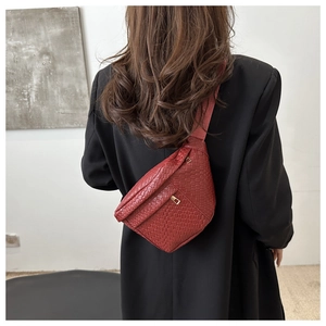 Detail of dark red woven texture crossbody bag worn over a black blazer for styling