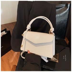 Detail of white embossed leather small square bag with floral texture and gold hardware