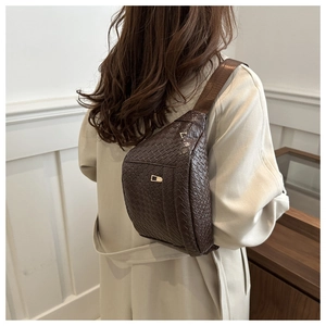Detailed close-up of dark brown woven texture crossbody bag with metal buckle closure