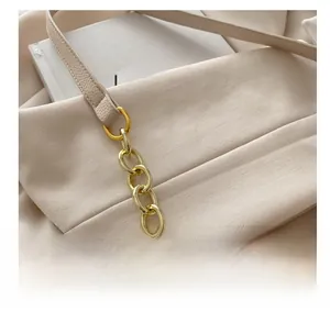 Détail du sac beige montrant la texture grainée et la bandoulière en chaîne dorée