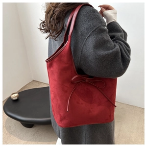 Détail du sac cabas en daim bordeaux avec un nœud délicat et une bandoulière minimaliste