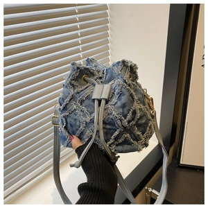 Detail of light blue denim bucket bag featuring raw edge patchwork and drawstring closure