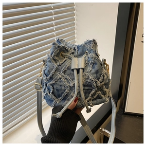 Detail of blue denim bucket bag with frayed quilted texture and golden hardware