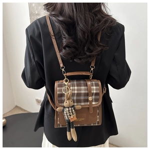 Brown plaid backpack with leather trim and cute rabbit charm shown on a female model