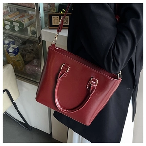 Détail du sac cabas bordeaux en cuir verni brillant avec boucles dorées et bandoulière