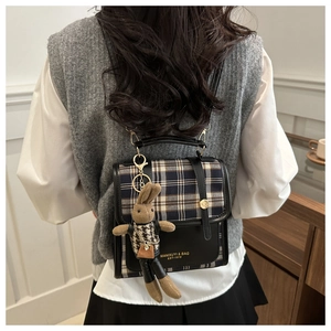 Detail of checkered fabric backpack with cute plush rabbit charm on model back