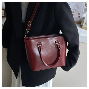 Détail du sac seau en cuir verni bordeaux avec garnitures dorées et bandoulière
