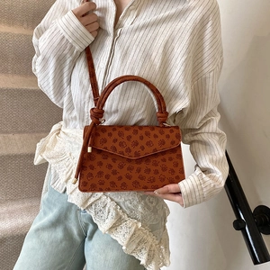 Brown orange square crossbody bag with embossed floral clover pattern and top handle