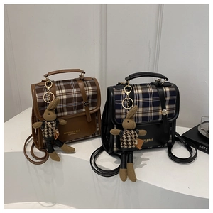 Detail view of British retro plaid backpacks in black and brown with a cute rabbit charm