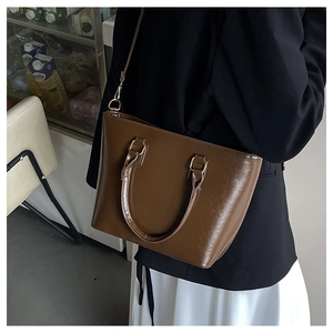 Gros plan détaillé d'un sac cabas marron en similicuir brillant avec des boucles en métal doré