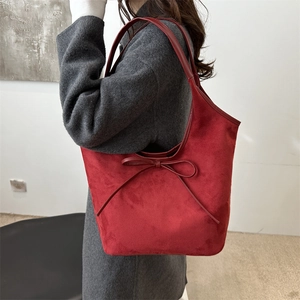 Sac fourre-tout rouge à nœud en daim élégant porté à l'épaule pour un look chic
