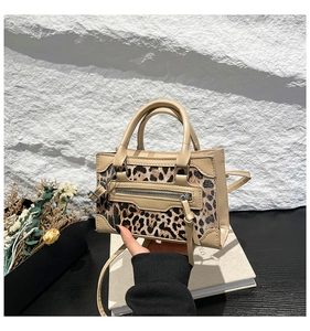 Detail of leopard print handbag featuring leather trim and long tassel zip pocket