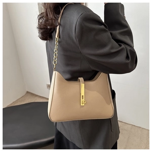 Détail du sac croissant beige avec fermoir doré et cuir texturé sur blazer gris