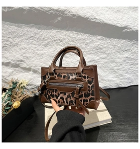 Detail of leopard print patchwork handbag with decorative zippers and tassels on leather