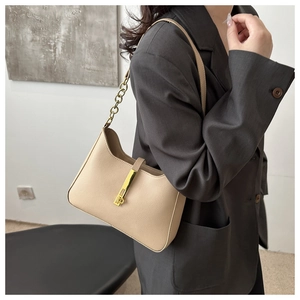Détail du sac hobo en cuir beige avec bandoulière en chaîne dorée et fermoir en métal