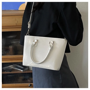 Détail d'un sac seau blanc minimaliste avec ferrures dorées et poignée supérieure