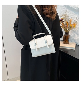 White retro satchel bag shown on model highlighting compact size and textured leather