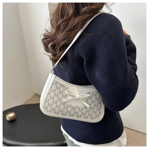 Detail of cream shoulder bag featuring M-pattern jacquard and a 3D bow decoration
