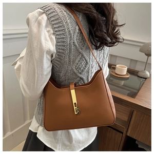 Détail du sac demi-lune en cuir marron texturé avec boucle métallique dorée élégante