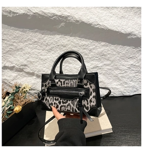 Detail of leopard print paneled handbag featuring black leather trim and long tassel zippers