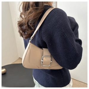 Close-up of a beige leather hobo bag featuring a decorative silver square buckle accent