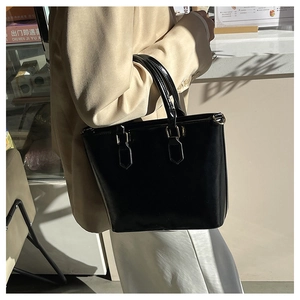 Détail d'un sac seau en cuir verni noir brillant avec finitions argentées chic